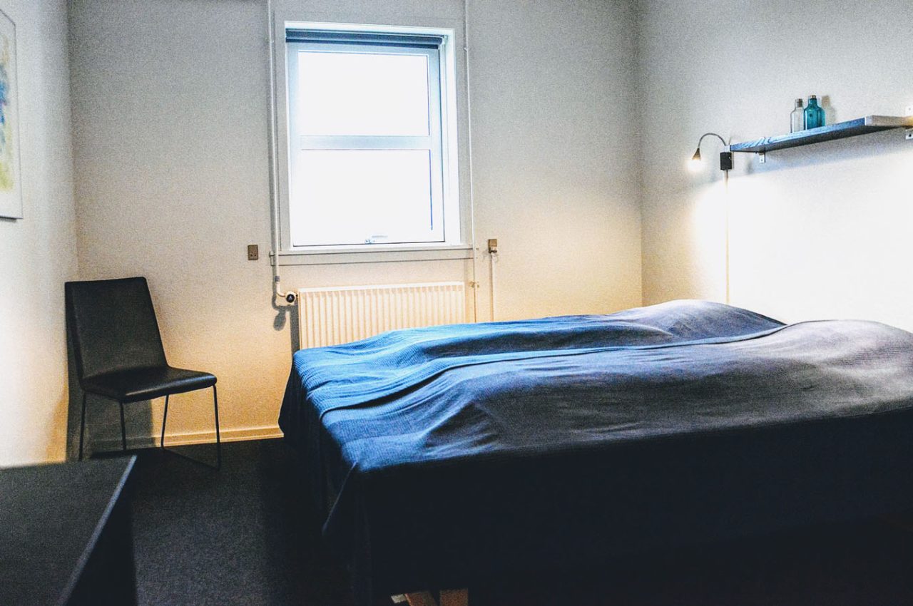 Dobbeltværelse med senge, stol og vindue som kan benyttes når du overnatter på vores vandrerhjem i Svendborg