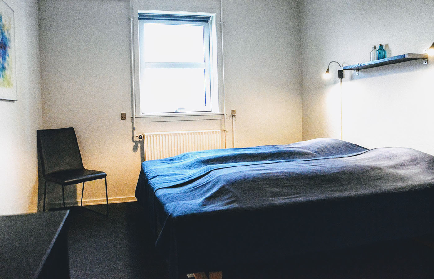 Dobbeltværelse med senge, stol og vindue som kan benyttes når du overnatter på vores vandrerhjem i Svendborg