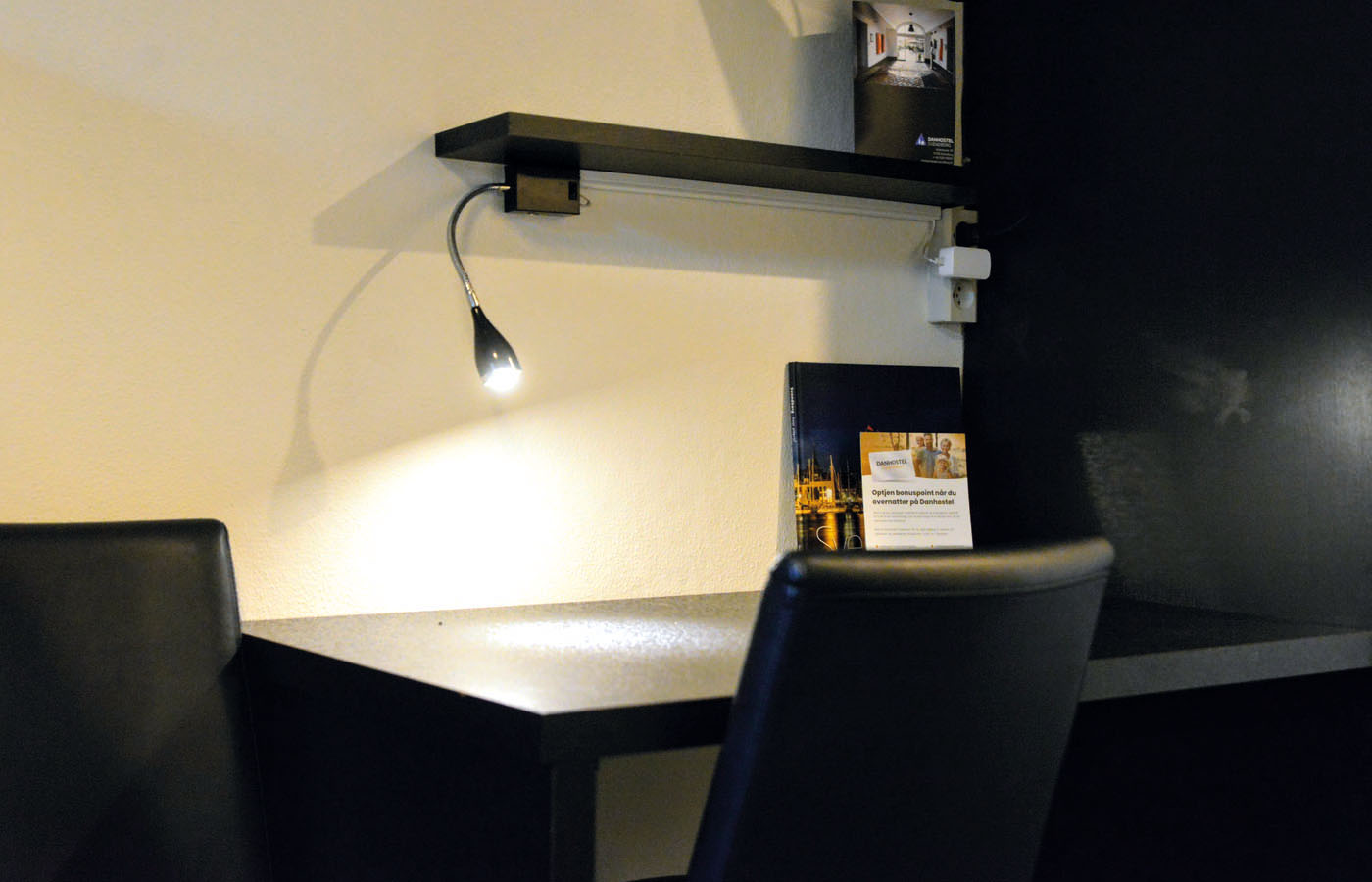 læselampe der oplyser bordet på et enkeltværelse, som kan benyttes, når du overnatter hos Danhostel Svendborg