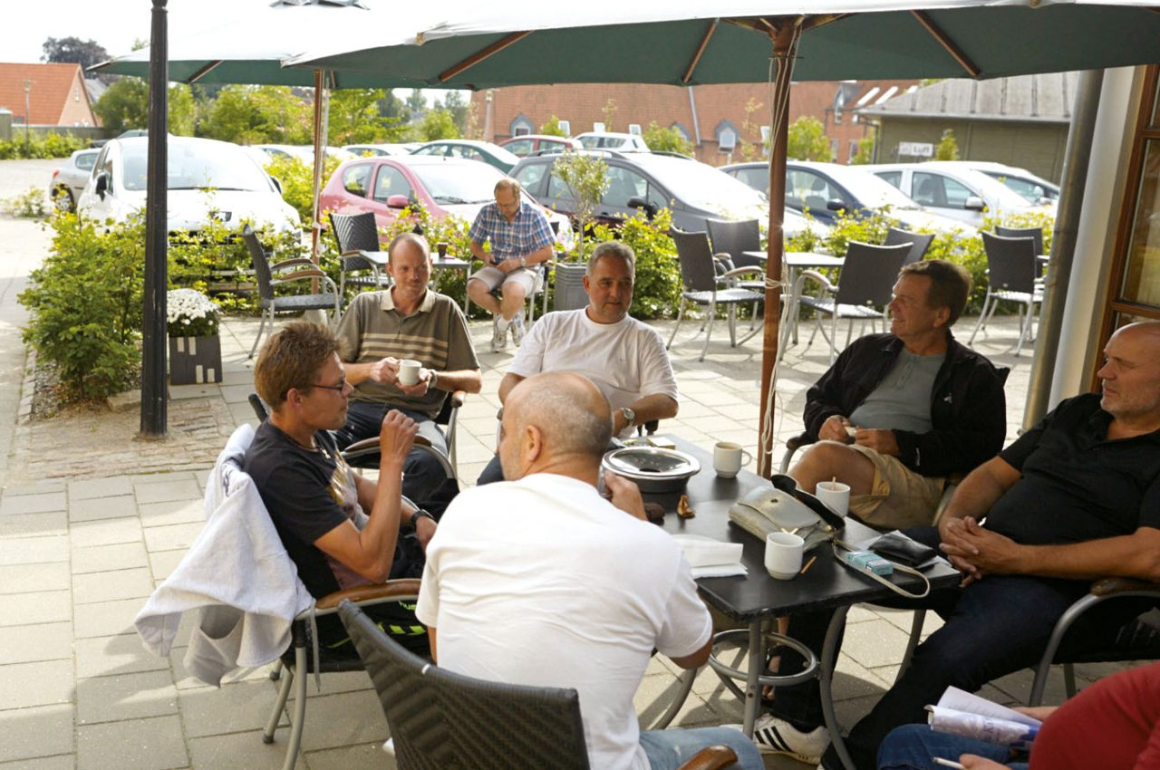 mænd samlet ved bord uden parasol, som overnatter på vandrerhjemmet i Svendborg under et familietræf